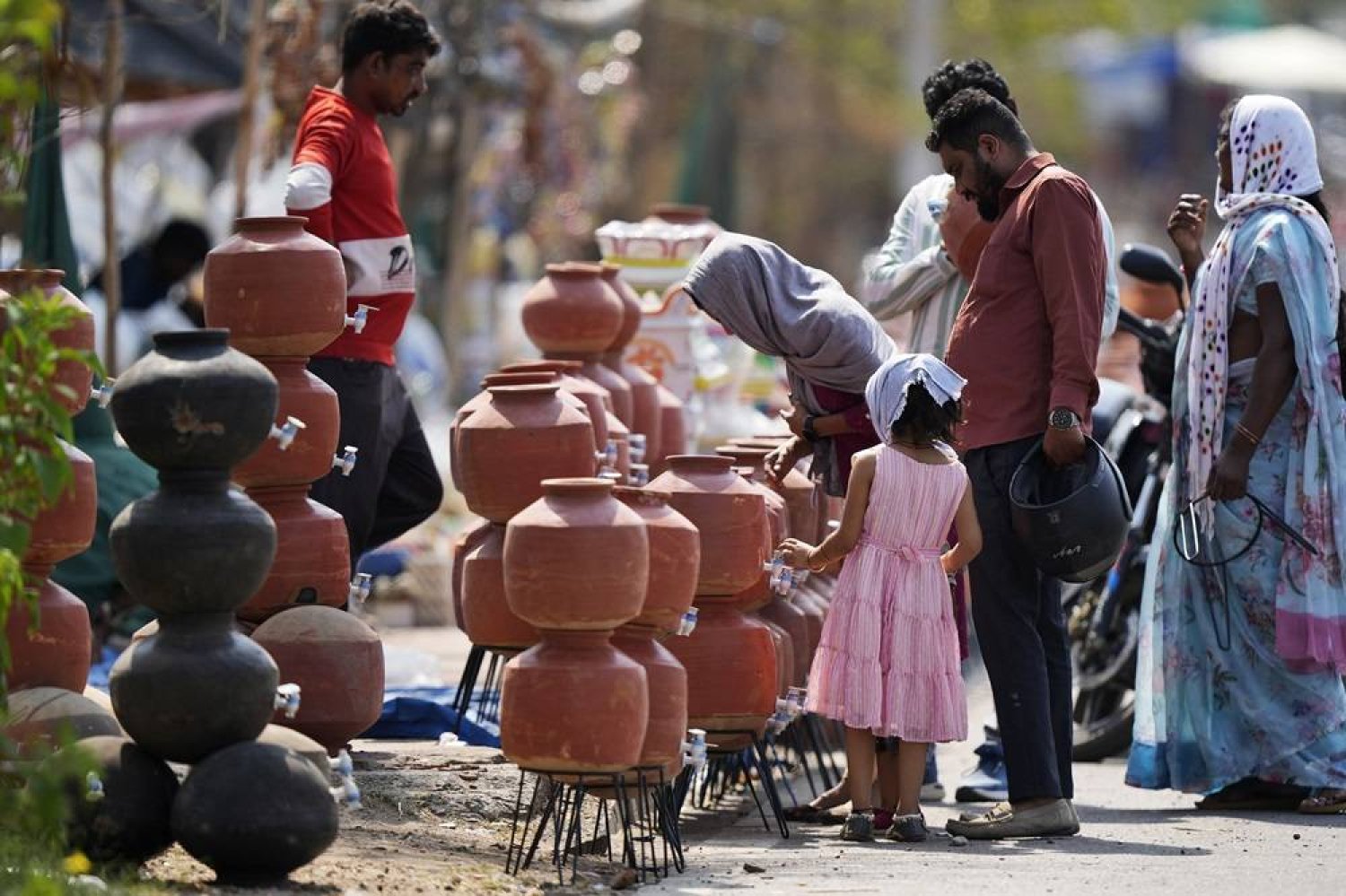  People shop for earthen water vessels, known locally as poor man's refrigerator, from a roadside vendor in Hyderabad, India, Thursday, May 2, 2024. (AP) 