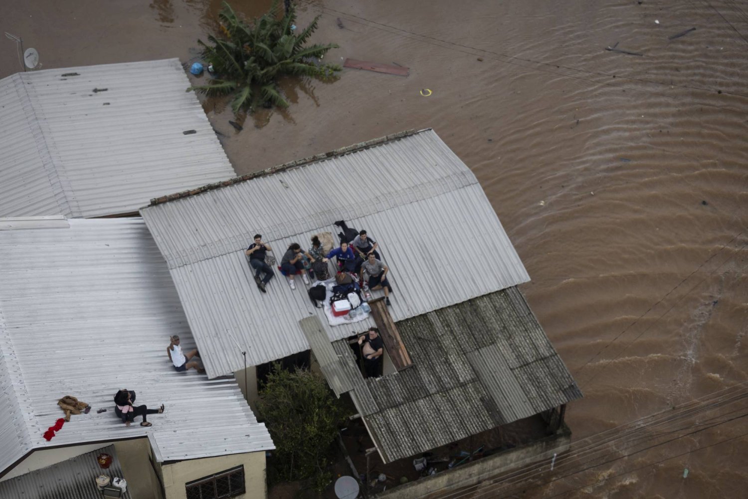 People wait to be rescued by a Brazilian Army helicopter during an operation in conjunction with firefighters to rescue people trapped in their homes due to a flood, in Canoas, Porto Alegre, Brazil, 04 May 2024. EPA/Isaac Fontana