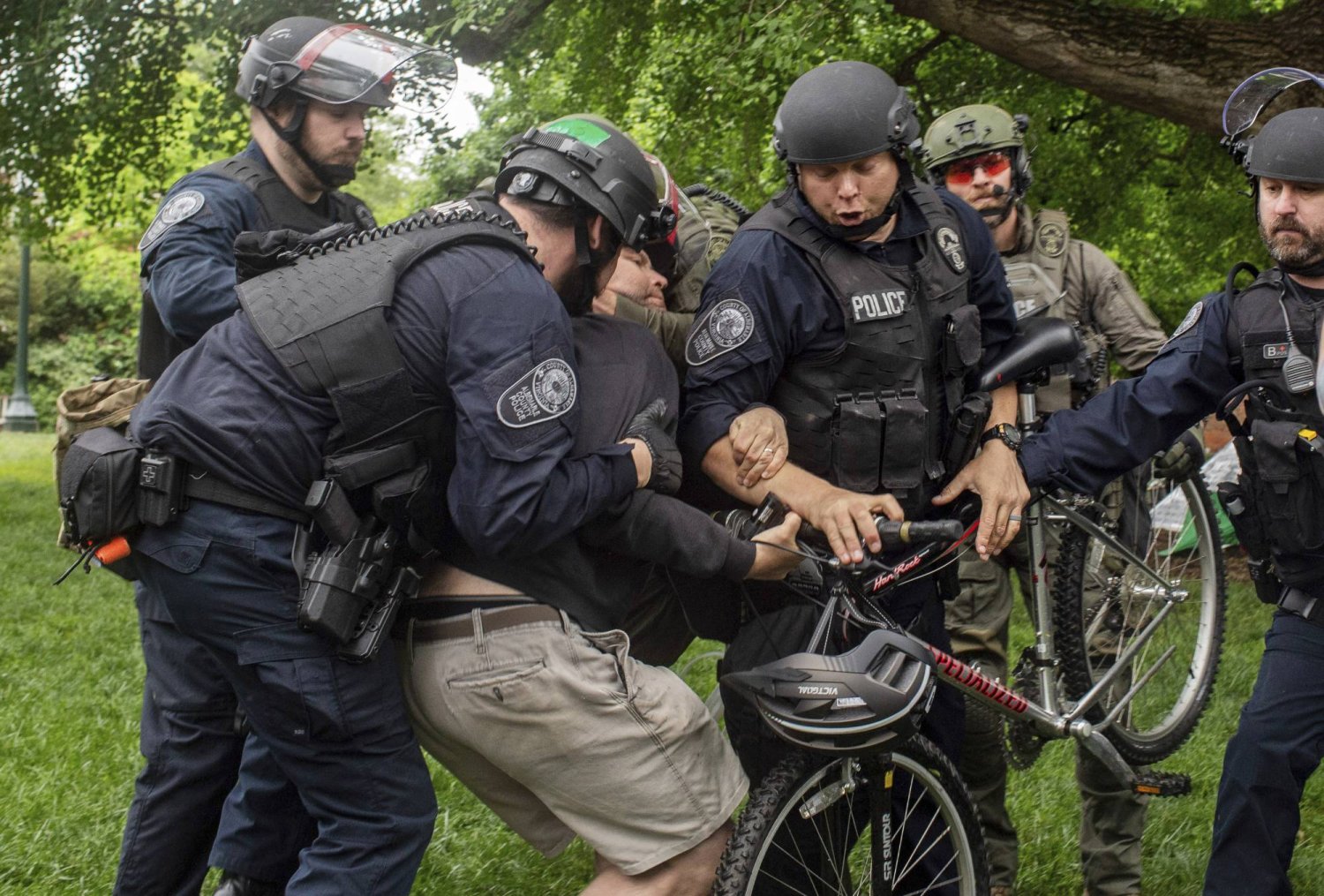 Police grab a protester with his bicycle on the campus of the University of Virginia, in Charlottesville, Va., where tents are set up, Saturday, May 4, 2024. (Cal Cary/The Daily Progress via AP)