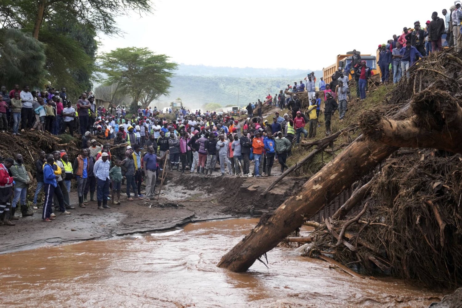 People gather on a bridge where a woman's body was retrieved, after floodwater washed away houses, in Kamuchiri Village Mai Mahiu, Nakuru County, Kenya, Tuesday, April 30, 2024. (AP Photo/Brian Inganga)