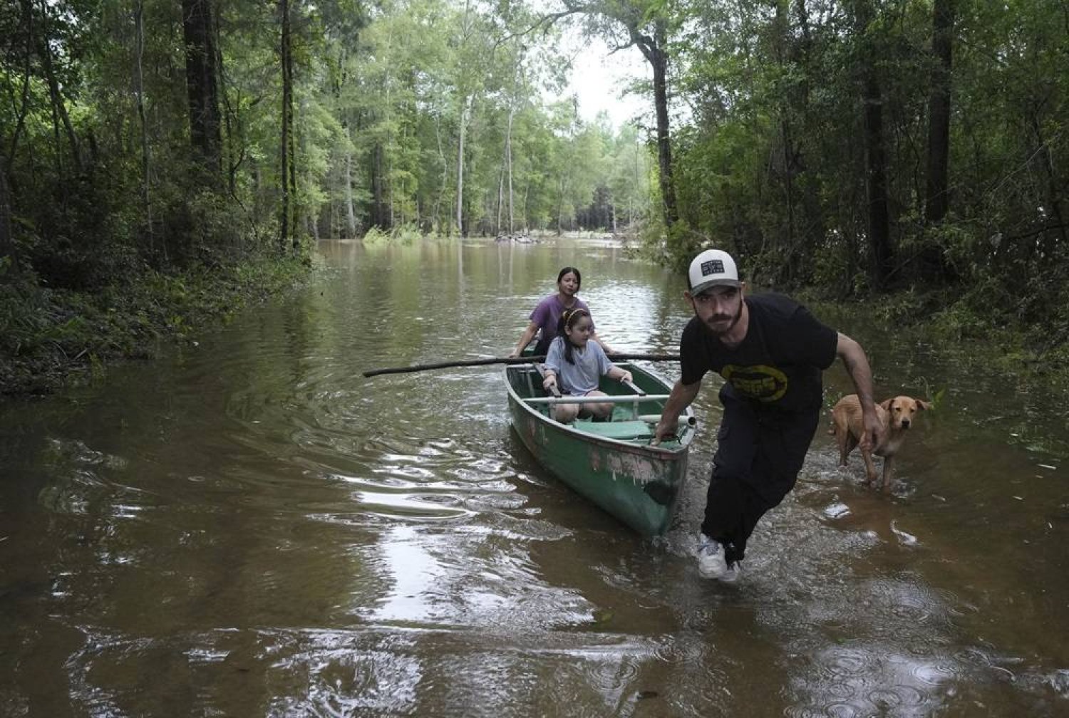Alvaro Trevino pulls a canoe with Jennifer Tellez and Ailyn, 8, after they checked on their home on Sunday, May 5, 2024, in Spendora, Texas. (Elizabeth Conley/Houston Chronicle via AP) 