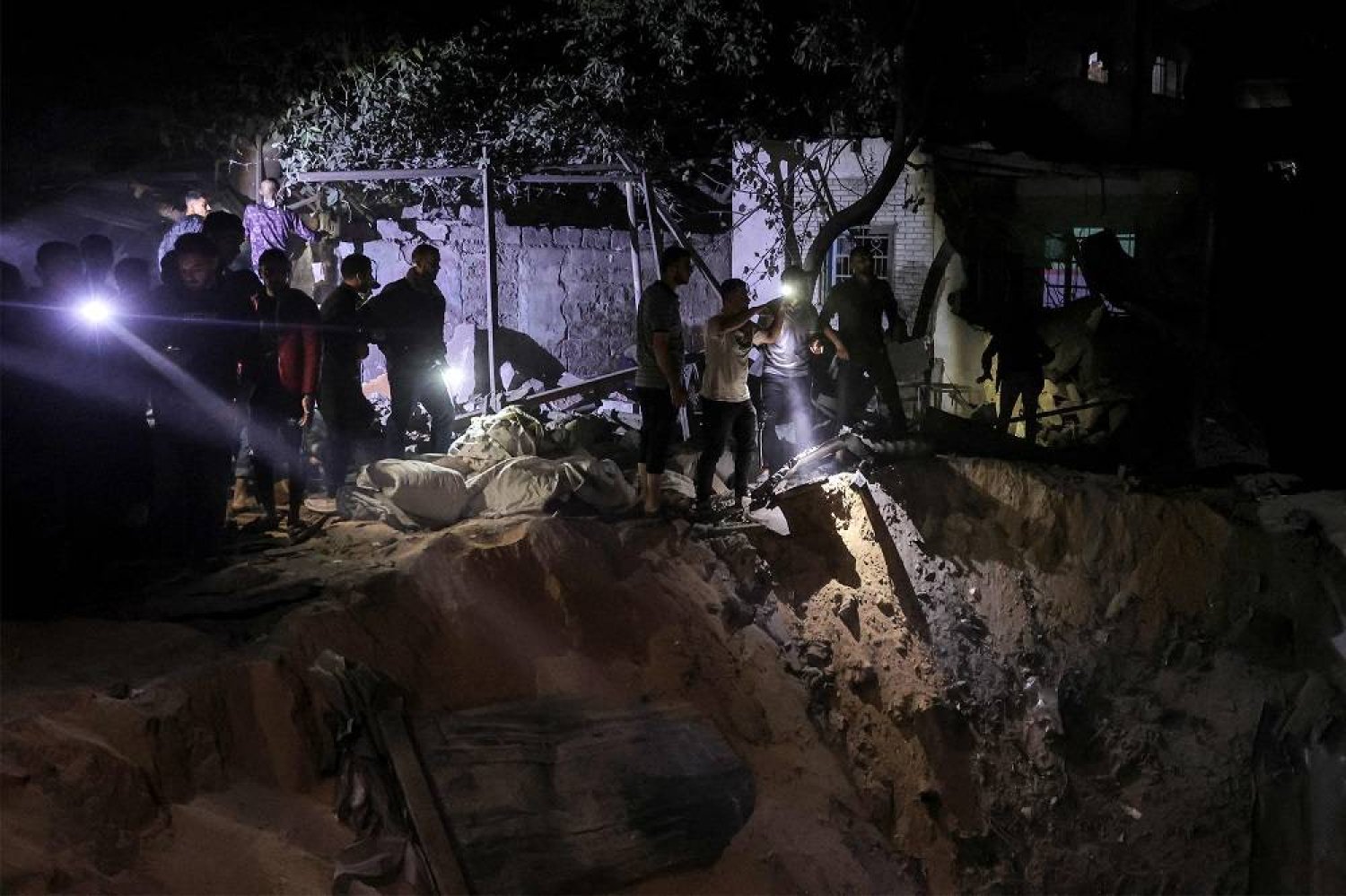 People search with flashlights by an impact crater at the site of a building that was hit by Israeli bombardment in Rafah in the southern Gaza Strip on May 7, 2024 amid the ongoing conflict in the Palestinian territory between Israel and Hamas. (AFP)
