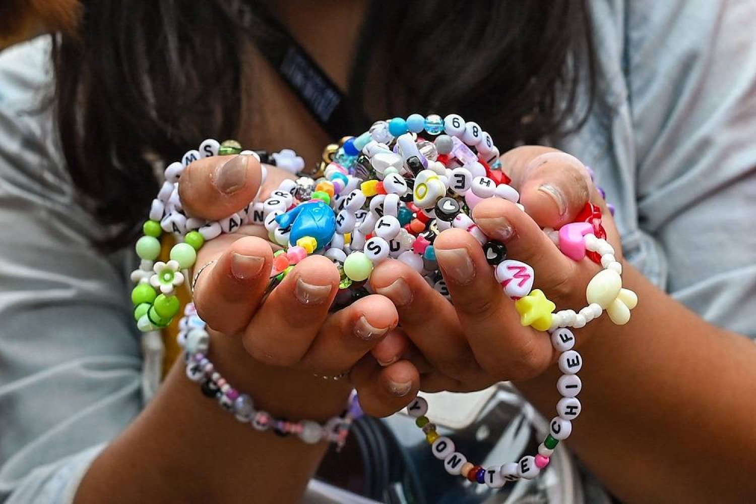 A fan of US singer Taylor Swift, also known as a Swiftie, holds friendship bracelets as she arrives for the first of the pop star's six sold-out Eras Tour concerts at the National Stadium in Singapore on March 2, 2024. (AFP)