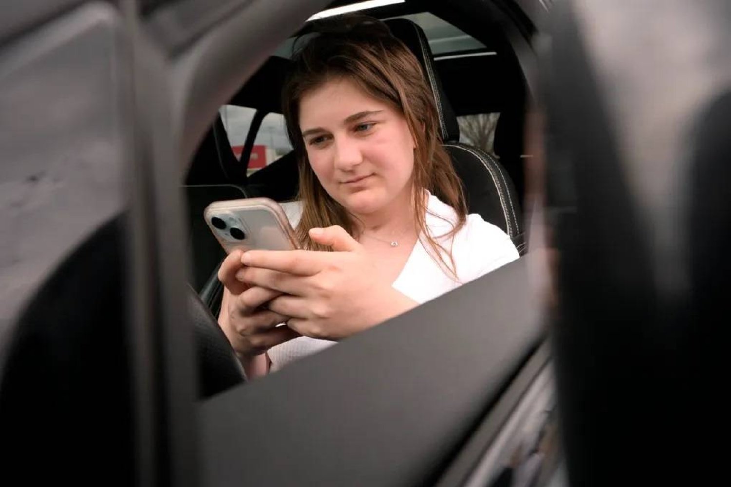 Alexis Bogan, whose speech was impaired by a brain tumor, uses an AI powered smartphone app to create a audible drink order at a Starbucks drive-thru on Monday, April 29, 2024, in Lincoln, R.I. (AP Photo/Steven Senne) 