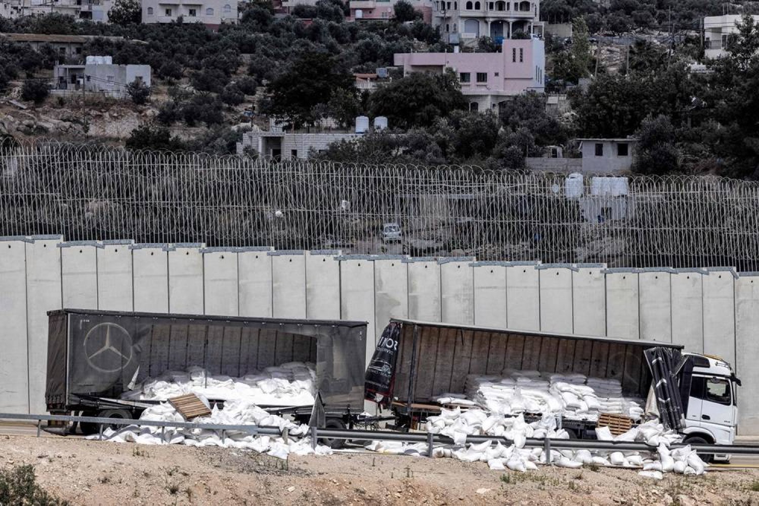A damaged trailer truck that was carrying humanitarian aid supplies is pictured along the Israeli side of Israel's controversial separation barrier with the West Bank near the village of Shekef on May 13, 2024, after it was vandalized by right-wing Israeli activists to protest against aid being sent to the Gaza Strip. (AFP) 