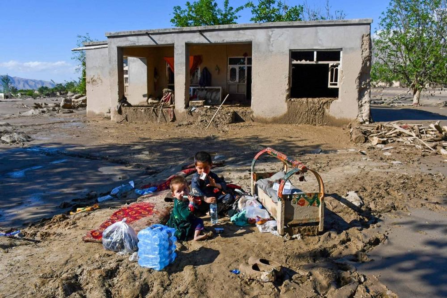 Afghans sit at their damaged house after floods in Burka district of Baghlan province on May 12, 2024. (AFP) 